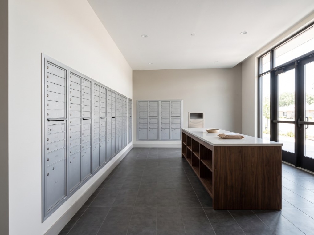 Buzones 4C de aluminio empotrados, con casilleros para paquetes, en una sala de correo de apartamentos recién terminada